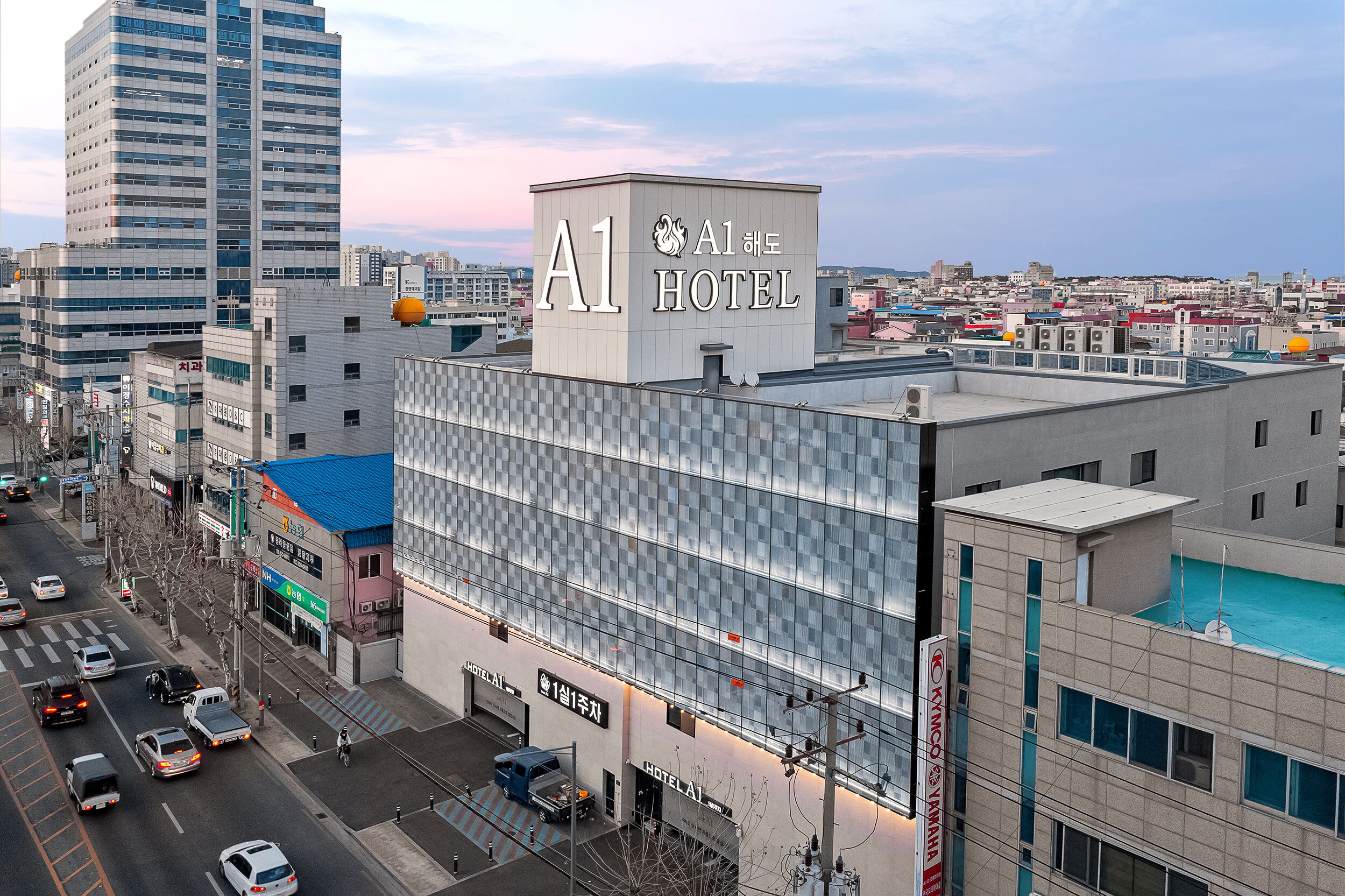 A modern hotel with a prominent A1 sign, a rooftop pool, and a view of the cityscape.