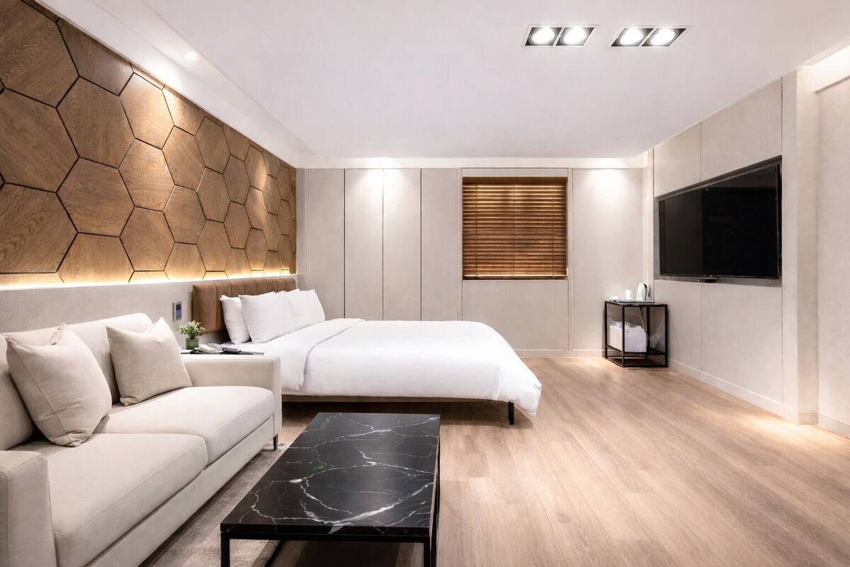 A modern hotel room with a bed, sofa, and a flat-screen TV.