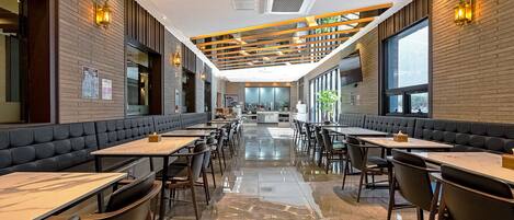 A restaurant with a long counter, booths, and a high ceiling with wooden beams.