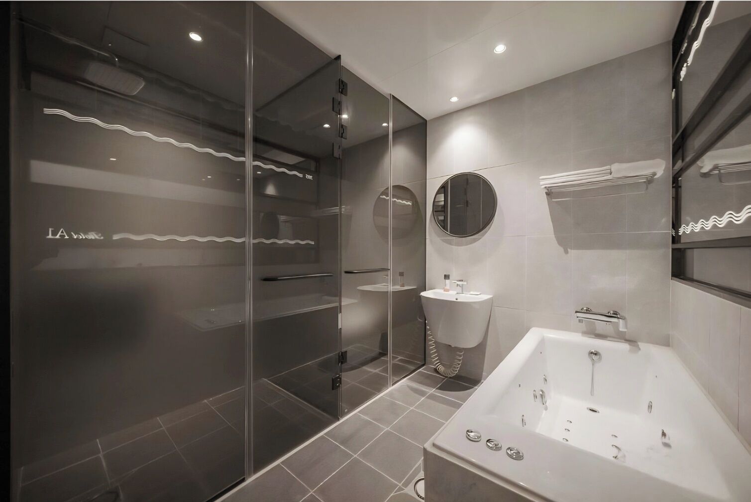 A modern bathroom with a glass shower enclosure, a standalone bathtub, and a round mirror.