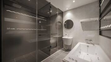 A modern bathroom with a glass shower enclosure, a standalone bathtub, and a round mirror.