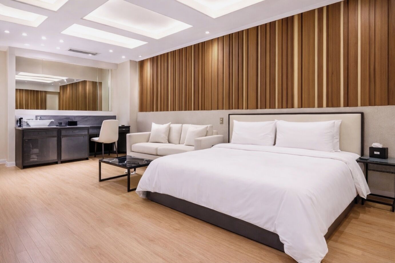 Una habitación de hotel moderna con una cama grande, un sofá, un escritorio y un espejo.