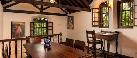 A dining area with a wooden table and chairs, a decorative vase, and a painting on the wall.