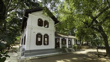 Traditional building with a central entrance and symmetrical facade, surrounded by mature trees.