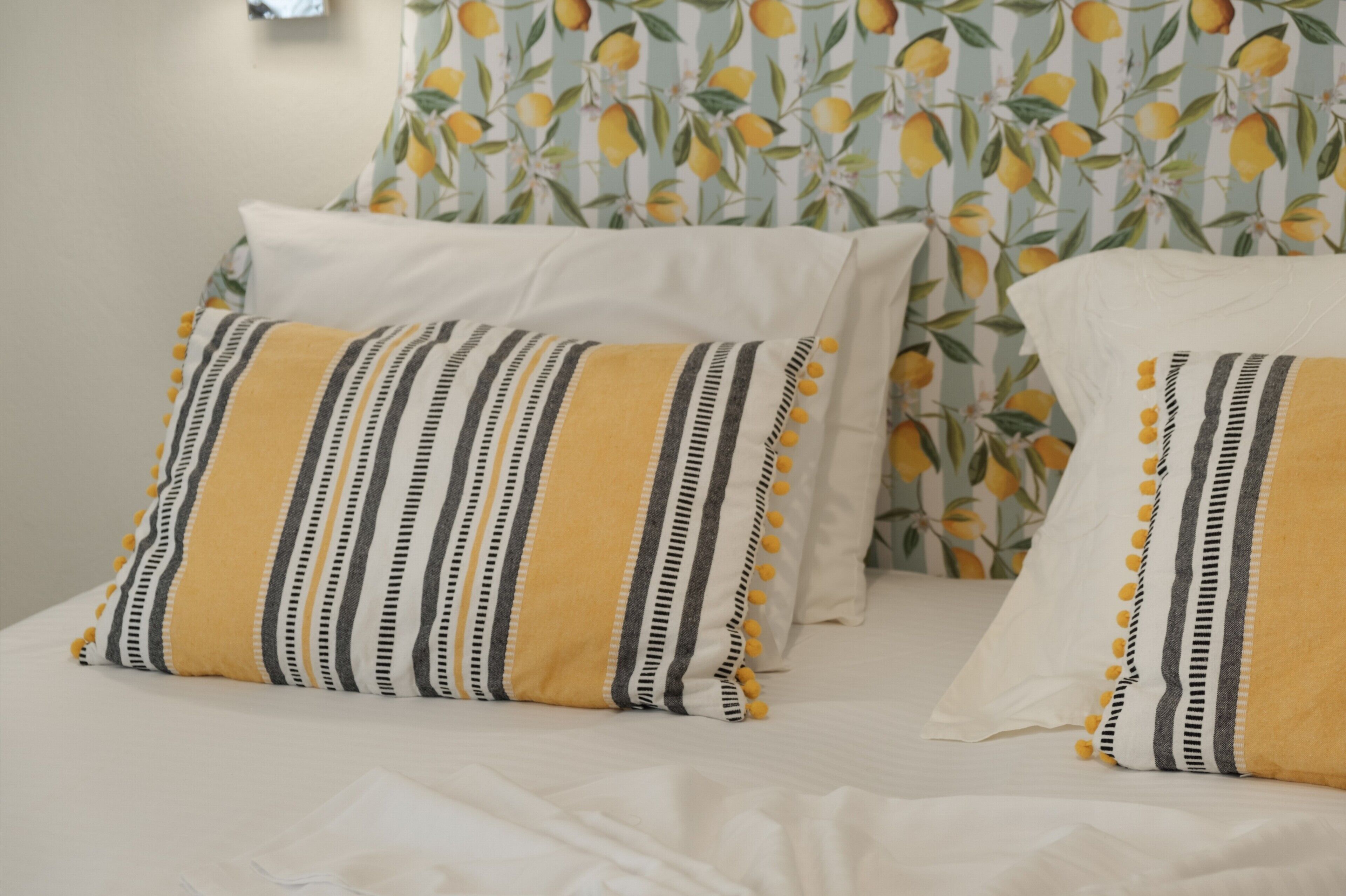 Cama com roupa de cama branca e duas almofadas estampadas.