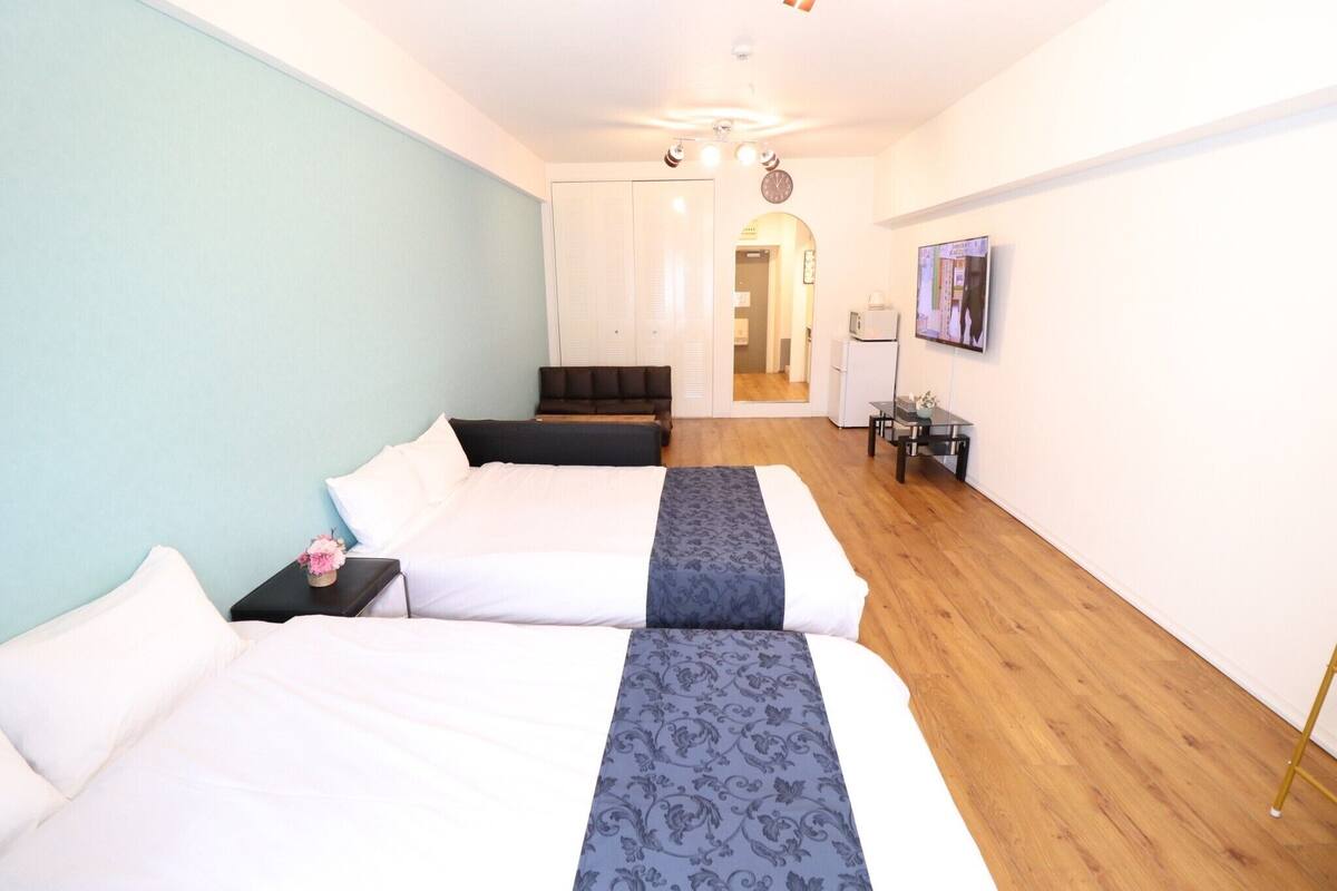 Habitación de hotel con dos camas, un escritorio y televisión.