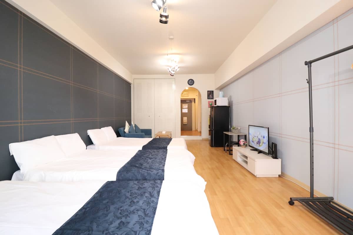 Una habitación de hotel con tres camas, televisión, escritorio y armario.