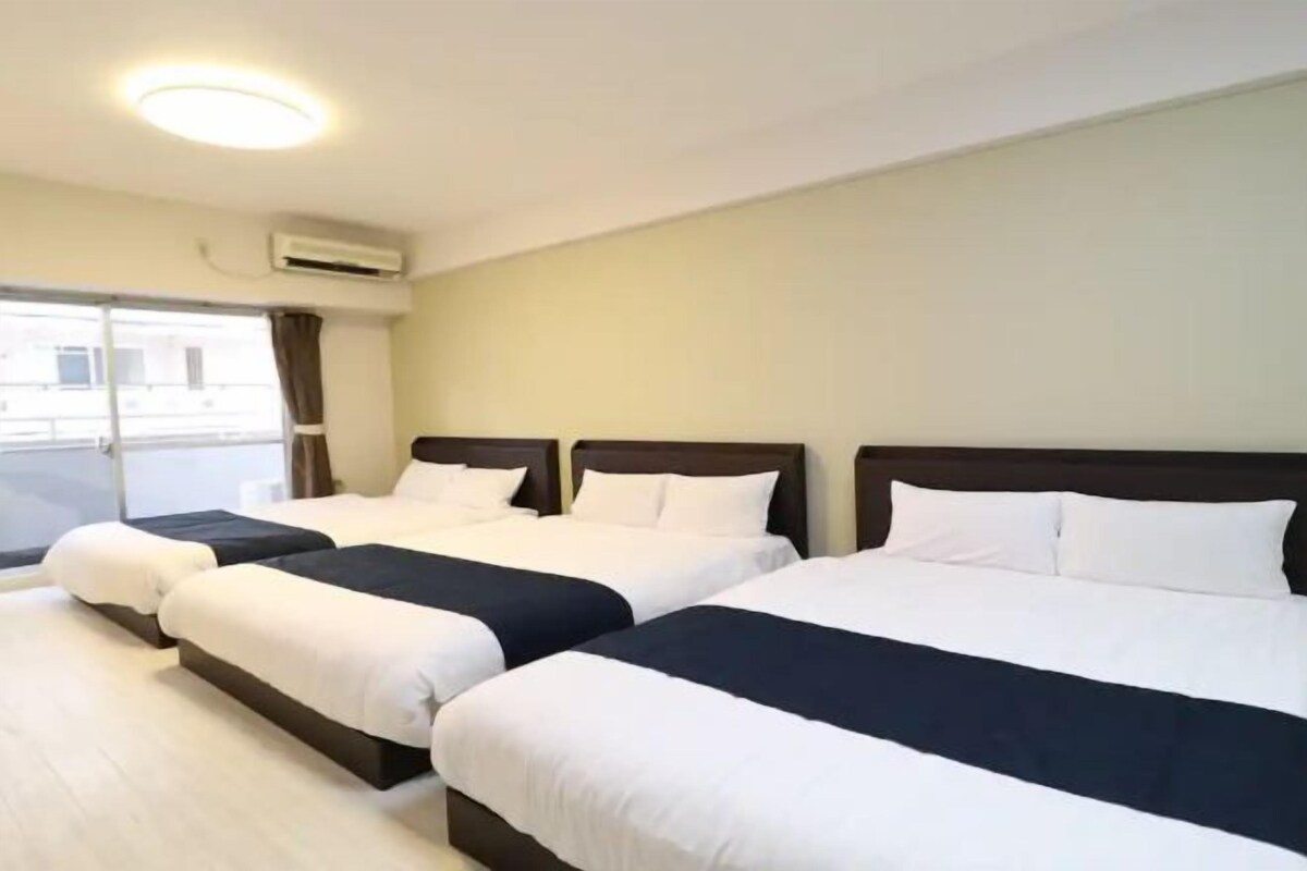 Een hotelkamer met drie bedden, een groot raam en een airconditioning.