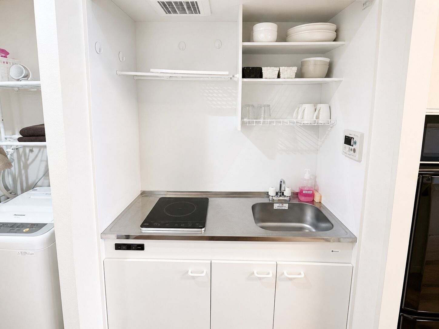 A compact kitchen with a built-in stove, a sink, and storage cabinets.