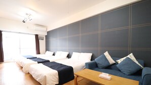 Une chambre d’hôtel avec deux lits, un canapé, une table en bois et une grande fenêtre.