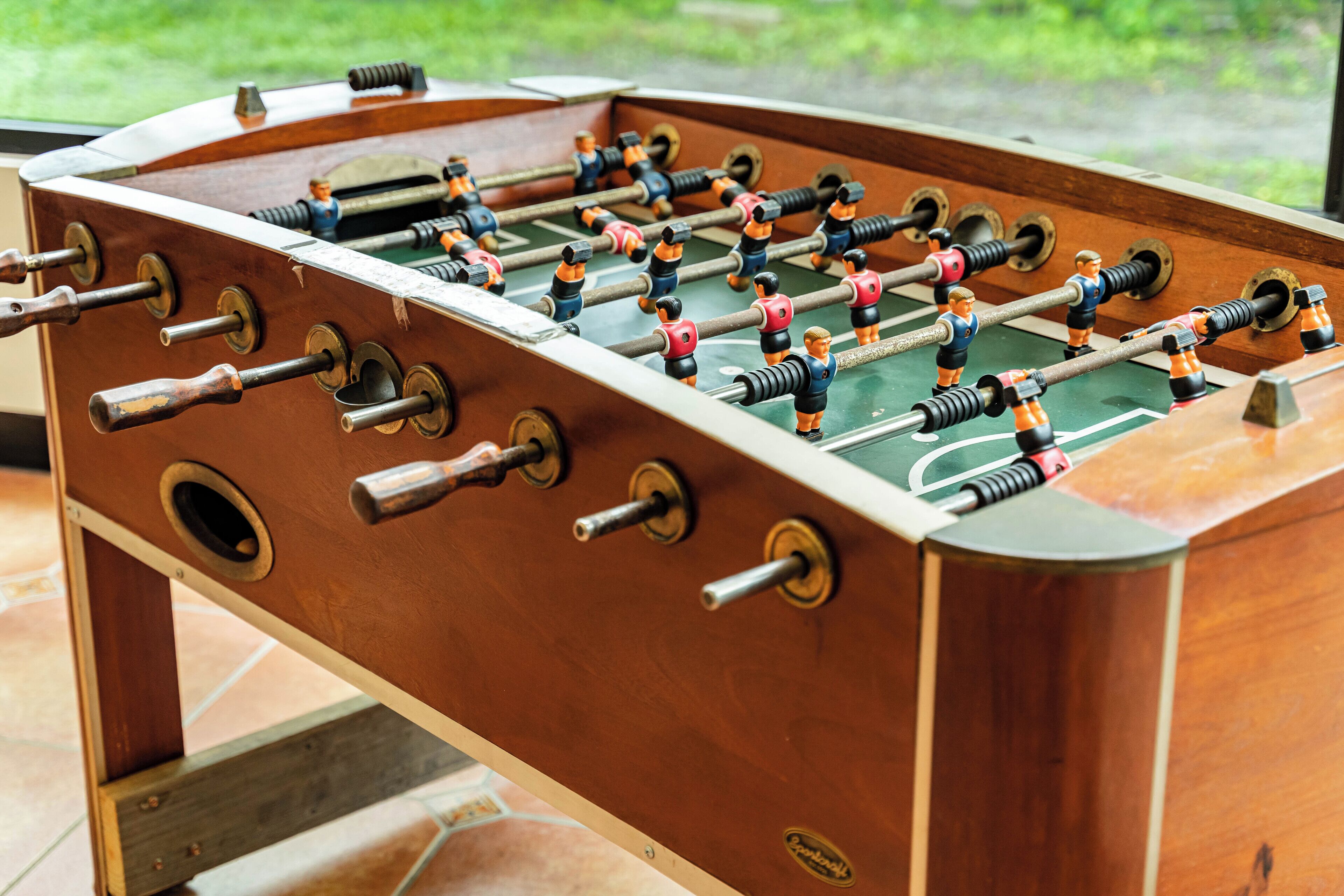 A wooden foosball table with metal rods and plastic figures.