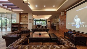 Ein modernes Wohnzimmer mit Ledersofas, einem Glastisch und einem großen Bildschirm, der eine Präsentation zeigt.