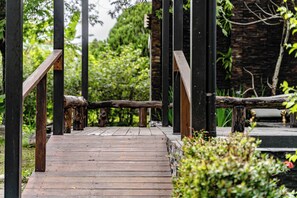 Un chemin en bois, bordé de rampes métalliques, mène à un bâtiment.
