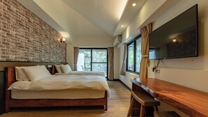 Ein modernes Hotelzimmer mit einer Ziegelwand, einem großen Bett, einer Holzbank, einem Flachbildfernseher und einem großen Fenster mit Vorhängen.