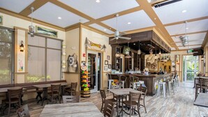 A spacious restaurant with high ceilings, wooden tables and chairs, a central bar area, and large windows allowing natural light. - Game Room House - Resort Access (Davenport)
