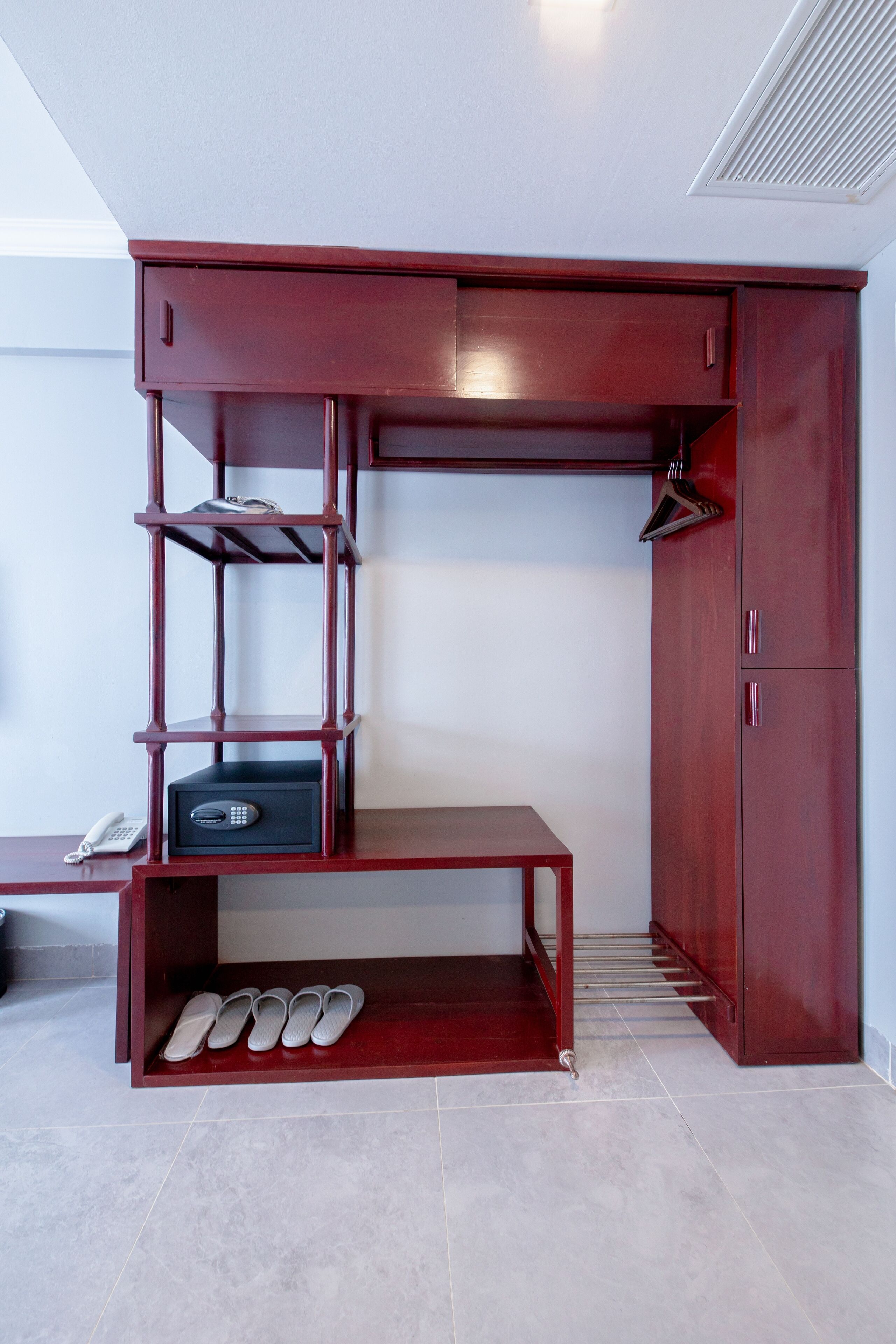 Une pièce compacte dotée d’une armoire intégrée, d’un porte-chaussures et d’une petite table avec un téléphone.