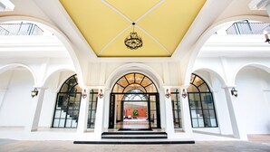 A grand entrance with a yellow ceiling, white arches, and a chandelier. - Solar hotel (Siem Reap)