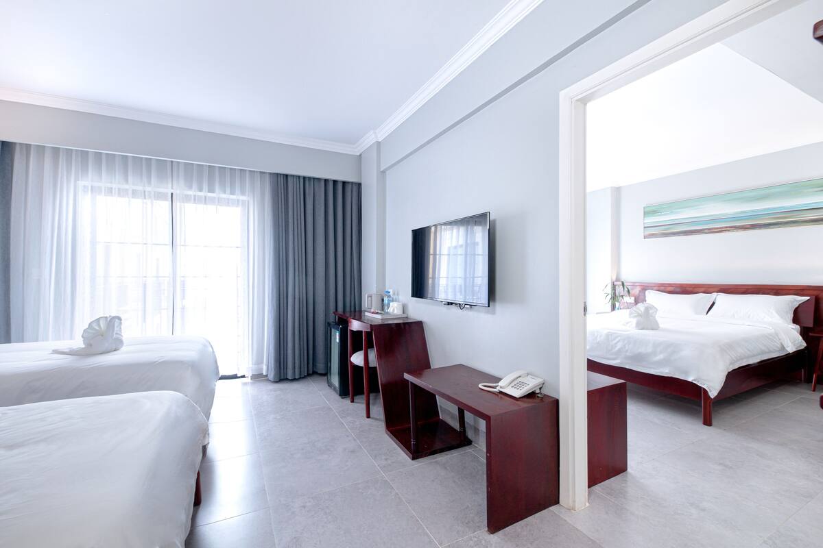 A hotel room with two beds, a desk, a phone, and a TV.