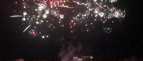 Schneebedeckte Landschaft mit einem Gebäude im Hintergrund und Feuerwerk am Himmel.