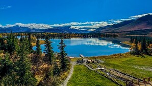 A lake surrounded by mountains, a clear sky, and a wooden deck with chairs. - Denali Lakeview Inn (Healy)