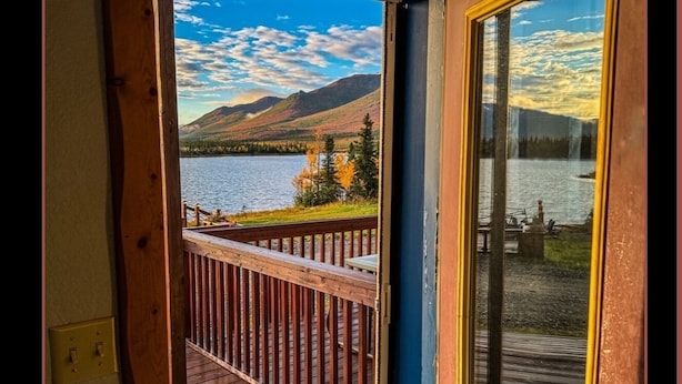 A wooden deck with a view of a lake and mountains. - Denali Lakeview Inn (Healy)