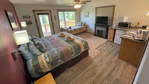 A bedroom with a bed, a desk, a television, and a fireplace. - Denali Lakeview Inn (Healy)