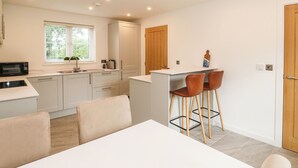 Una cocina moderna con armarios blancos, un microondas y una pequeña isla con taburetes.