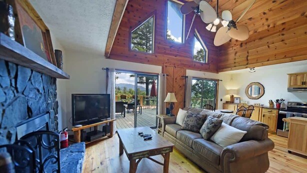 Ein gemütliches Wohnzimmer mit Kamin aus Stein, einem Fernseher, einer Couch und einem Essbereich mit Tisch und Stühlen.