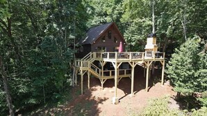 Eine Holzhütte mit einer Holterrasse, umgeben von dichtem Wald.