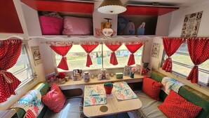 Un interior de autocaravana acogedor, con una mesa de comedor, zona de estar y varios objetos personales.