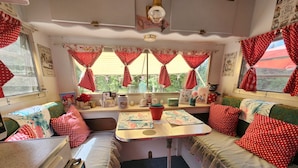 Un interior acogedor con comedor, kitchenette y zona de estar con cojines de lunares rojos.