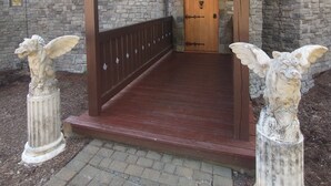 Un edificio de piedra con un porche de madera y techo verde.