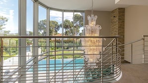 Un interior moderno con piscina, ventanas amplias y un candelabro decorativo.