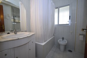 A bathroom with a large sink, a bidet, a mirror, and a window. - URBANIZACION MIRAMAR (1 BEDROOM) (Benidorm)