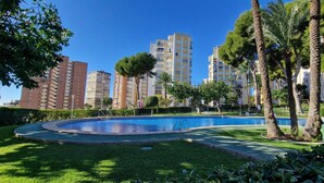 Un quartier résidentiel doté d’une piscine, entouré de verdure et avec de grands immeubles en arrière-plan.