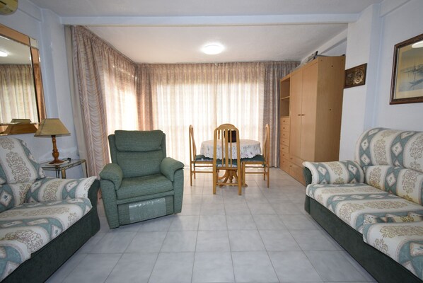 A living room with two sofas, a dining table with chairs, a wooden wardrobe, and a mirror. - URBANIZACION MIRAMAR (1 BEDROOM) (Benidorm)