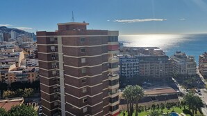 Un grand hôtel avec de nombreux étages, une antenne bien visible et une vue sur la mer.