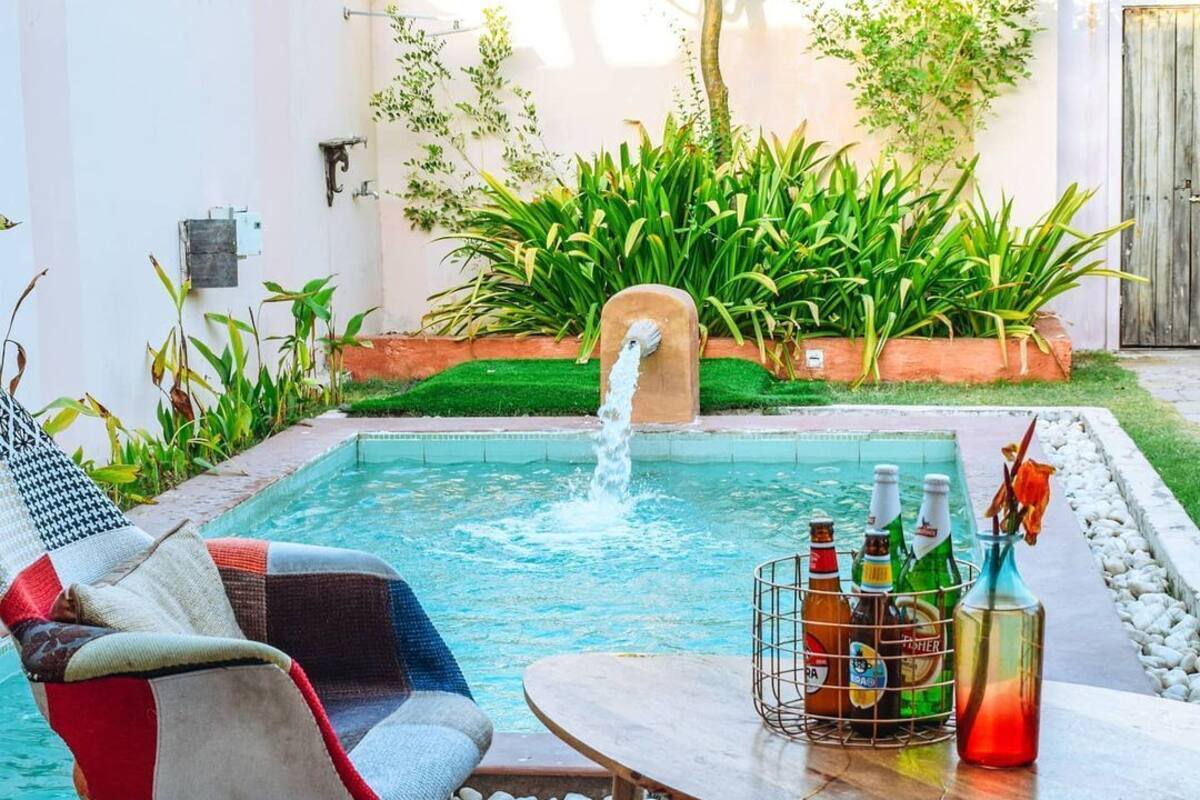 A poolside area with a lounge chair, a table with bottles, and a water feature.