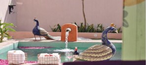 A decorative fountain with peacocks and a water feature in a landscaped outdoor area. - Parijat Private Pool Villa 1, 2 and 3 BHK (Udaipur)