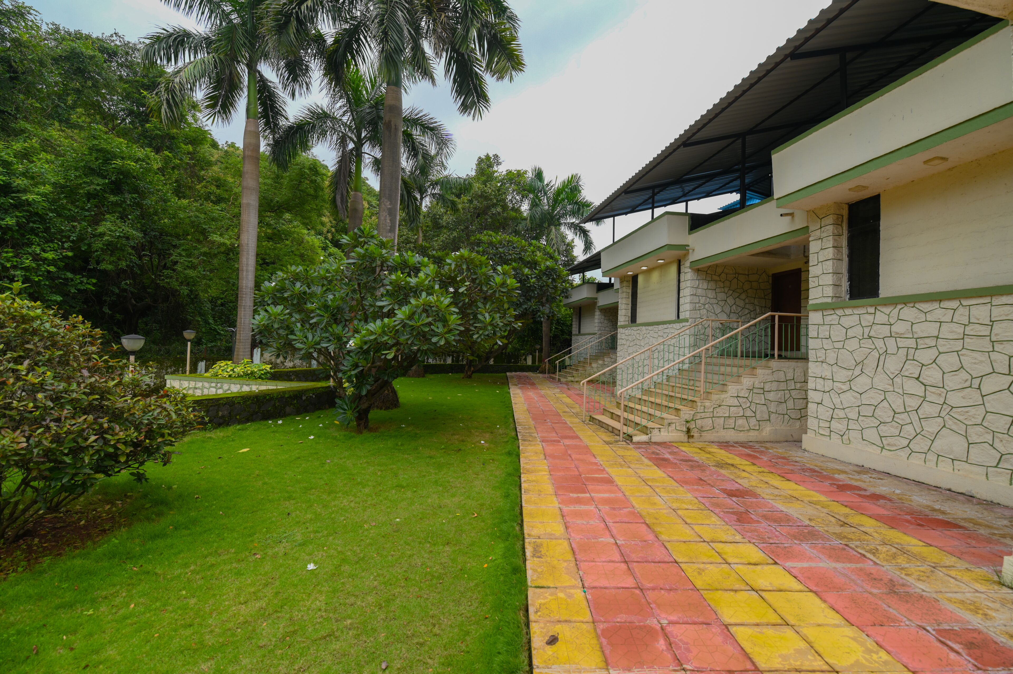 A building with a stone facade, a green lawn, and a staircase leading to a covered area.