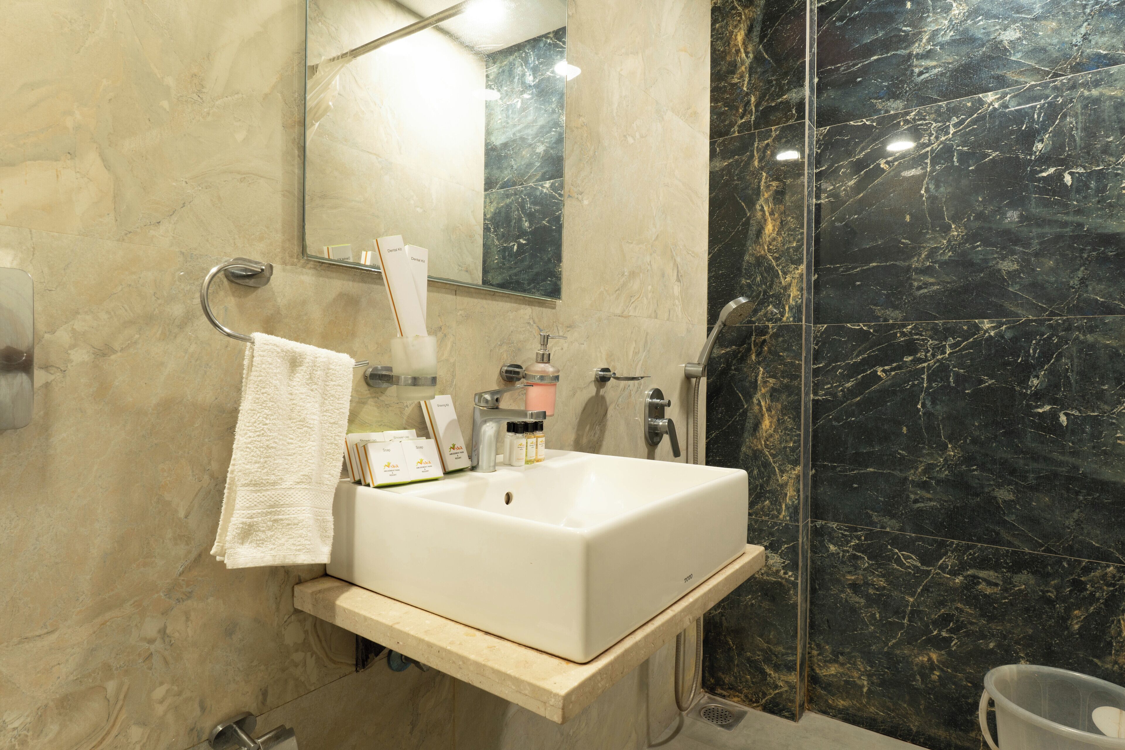 A bathroom with a white sink, a mirror, and a black marble wall.
