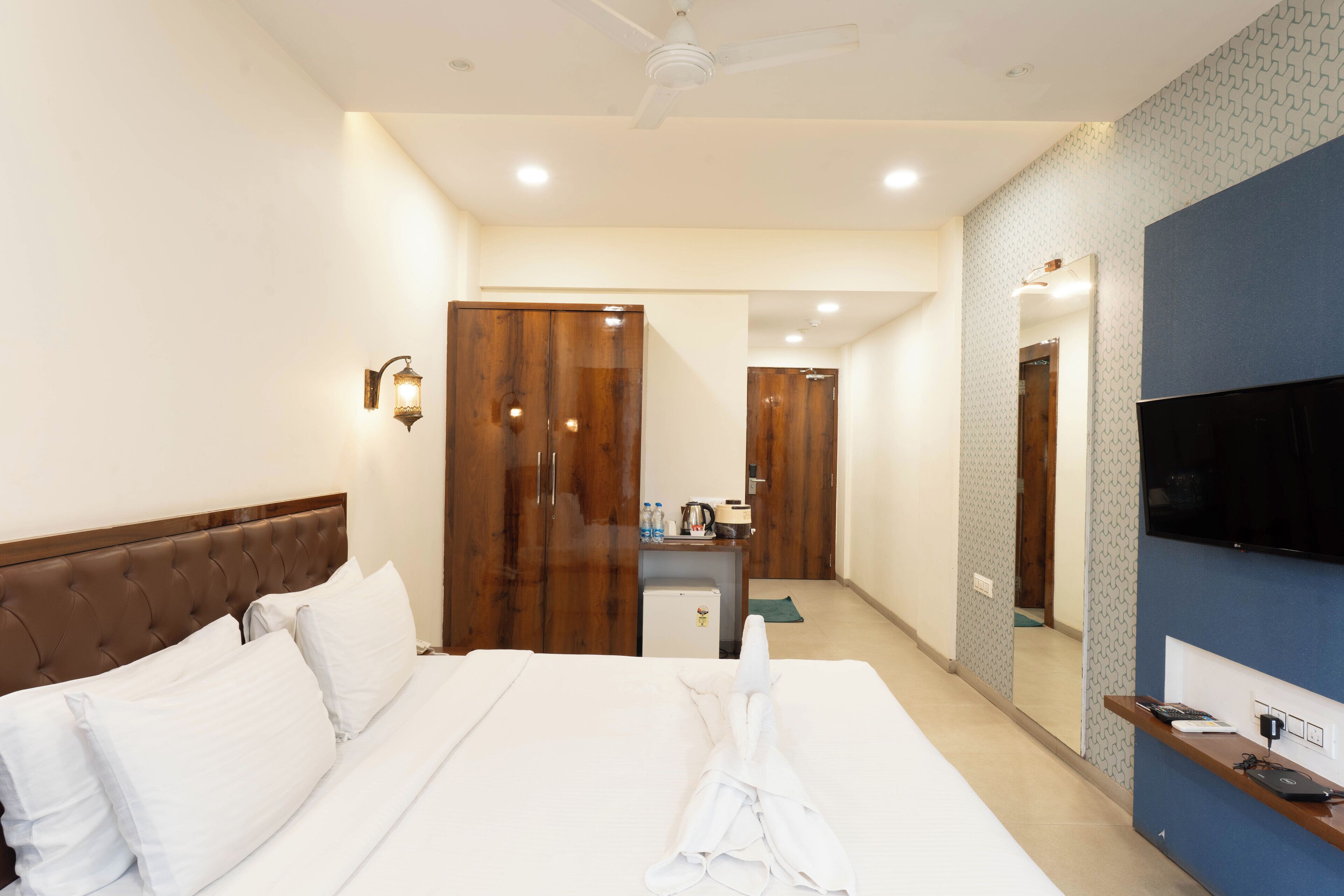 A hotel room with a bed, a desk, a television, and a wardrobe.