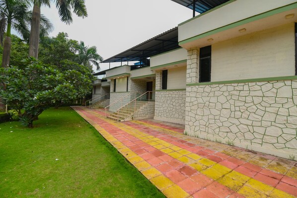 A building with a stone facade, a covered walkway, and a well-maintained lawn.
