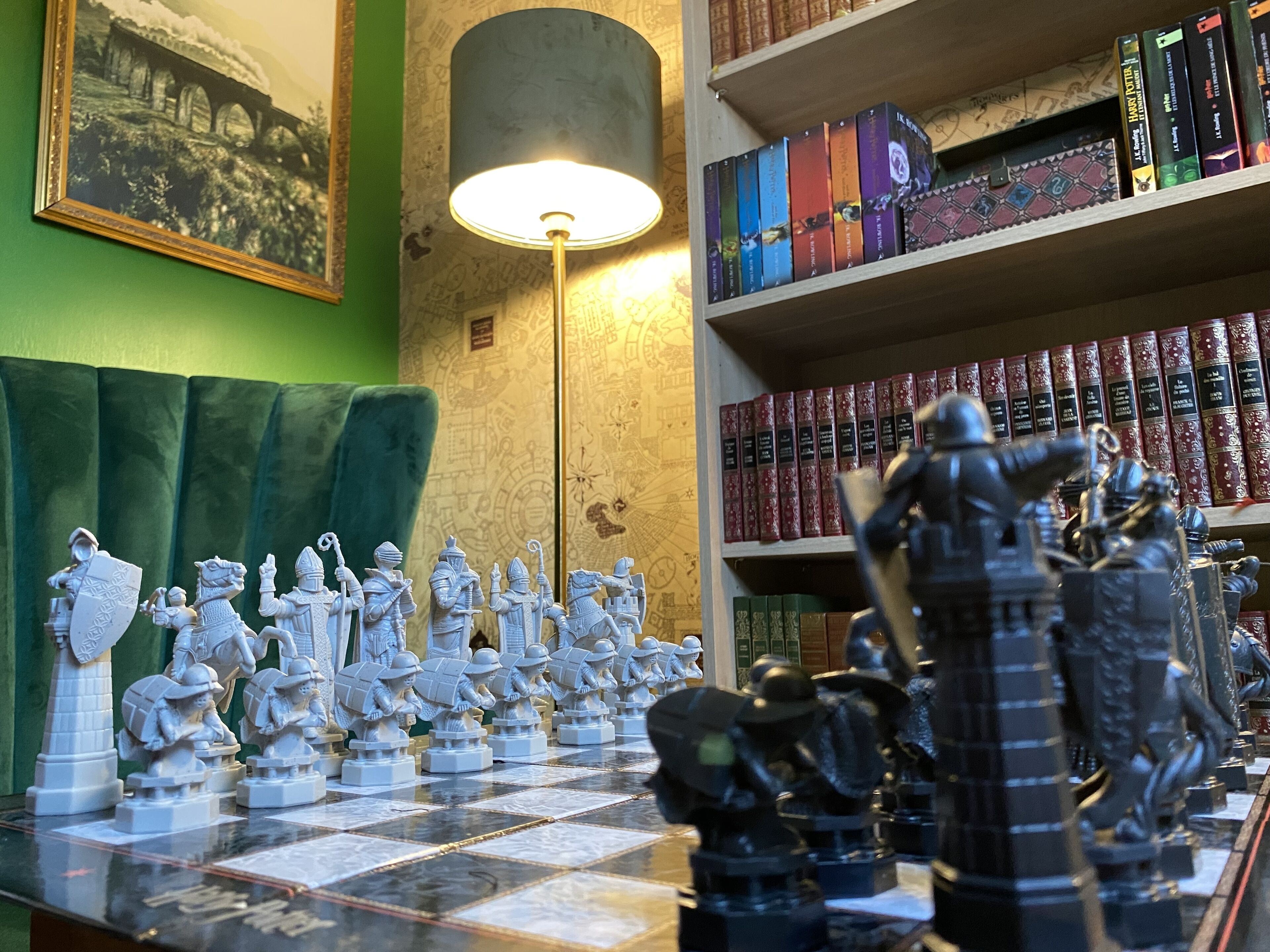 A chessboard with figurines, a lamp, and bookshelves with books.