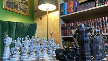 A chessboard with figurines, a lamp, and bookshelves with books.