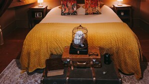 Un dormitorio con una cama grande, dos mesitas de noche, una maleta y una lámpara.
