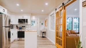 A modern kitchen with white cabinets, stainless steel appliances, and a central island. - Remodeled Copalis Beach cottage with fully fenced yard (Ocean Shores)