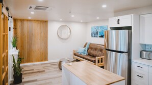 A modern kitchen with a refrigerator, a wooden dining table, and a sofa. - Remodeled Copalis Beach cottage with fully fenced yard (Ocean Shores)