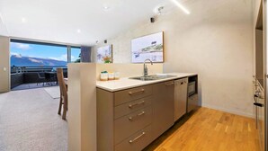 A modern kitchen with a large window, wooden flooring, and a view of the mountains. - Manaaki Alpine Retreat Central CBD ~ SPA ~ Garage (Queenstown)