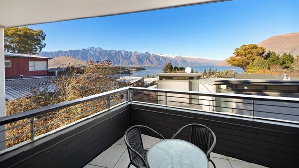 A balcony with a table and chairs, overlooking a mountainous landscape and a body of water. - Manaaki Alpine Retreat Central CBD ~ SPA ~ Garage (Queenstown)